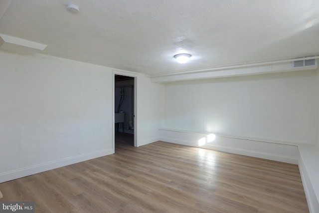 spare room with sink, light wood-type flooring, and a textured ceiling