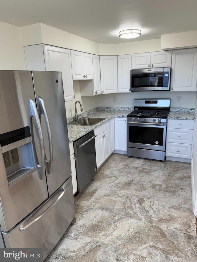 kitchen featuring light stone countertops, sink, white cabinets, and stainless steel appliances