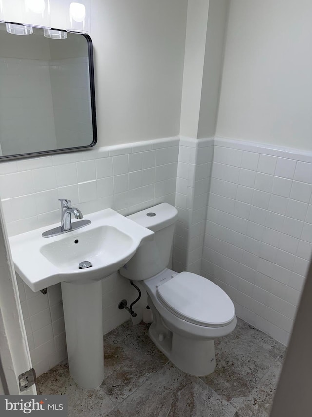 bathroom with tile walls and toilet