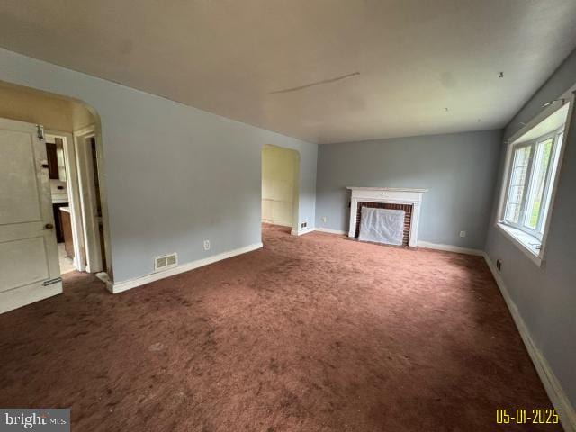 6410 Laurel Dr, Gwynn Oak, MD 21207 - unfurnished living room featuring arched walkways, carpet, and a brick fireplace