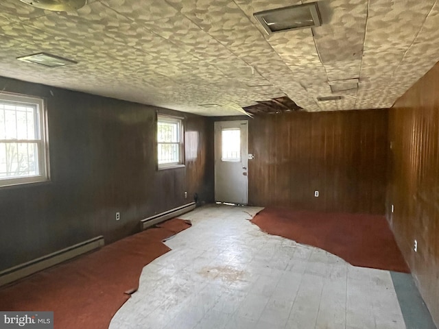 spare room with wooden walls and a baseboard heating unit