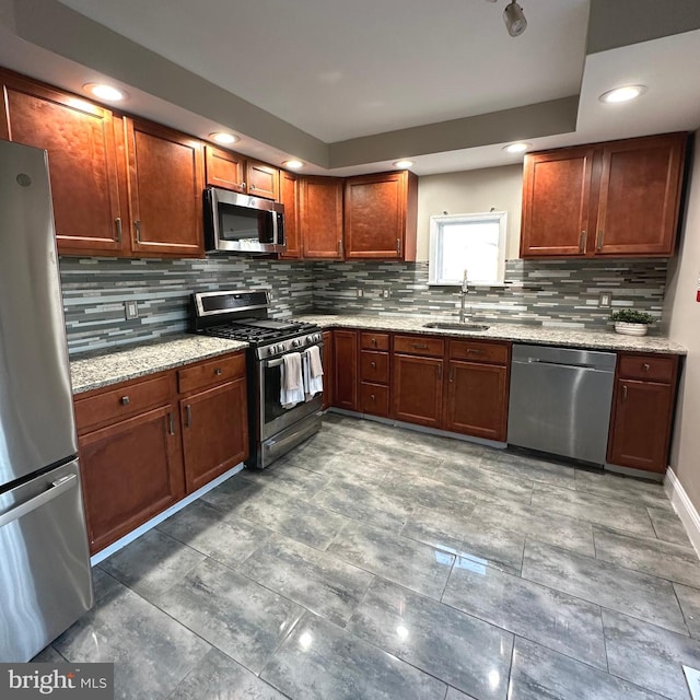 kitchen featuring backsplash, stainless steel appliances, light stone counters, and sink