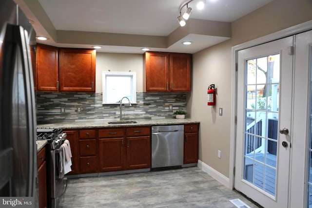 kitchen featuring a wealth of natural light, sink, light stone countertops, and appliances with stainless steel finishes