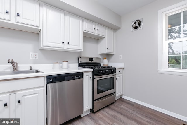 kitchen featuring sink, white cabinets, stainless steel appliances, and light wood-type flooring