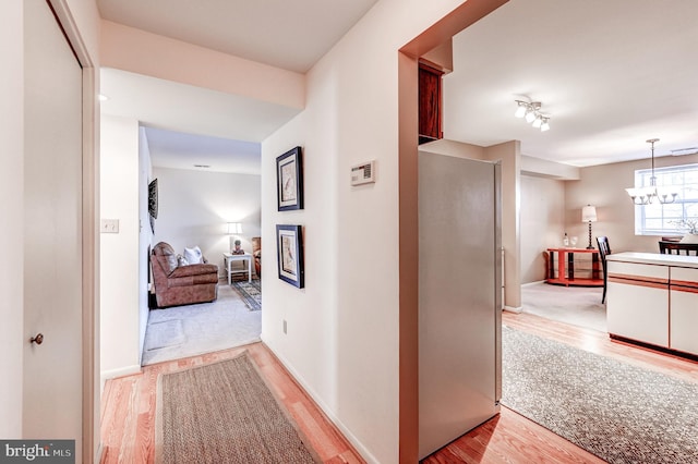 hall with a notable chandelier and light hardwood / wood-style flooring