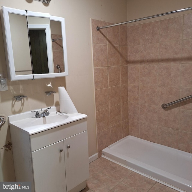 bathroom with tile patterned flooring, vanity, and tiled shower