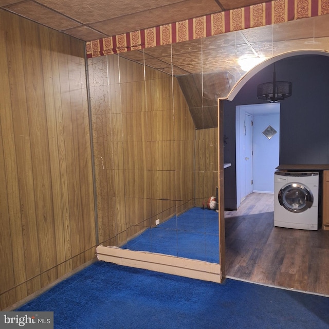 interior space featuring wood walls, dark wood-type flooring, and washer / clothes dryer