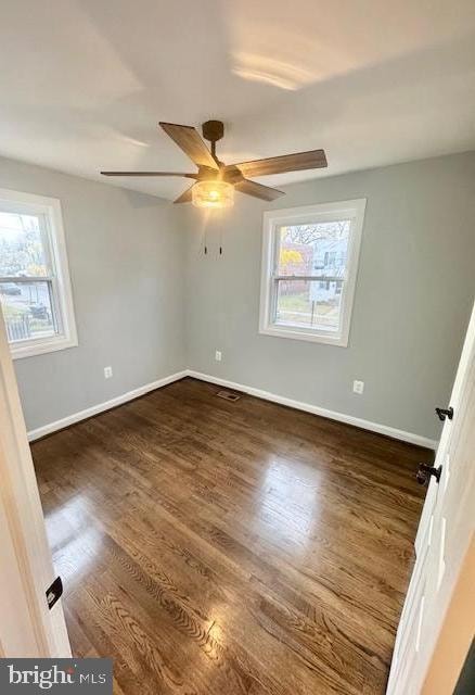 spare room featuring ceiling fan, plenty of natural light, and dark hardwood / wood-style floors