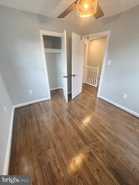 unfurnished bedroom with ceiling fan, dark wood-type flooring, and a closet