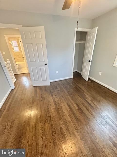 unfurnished bedroom with ceiling fan, a closet, and dark wood-type flooring