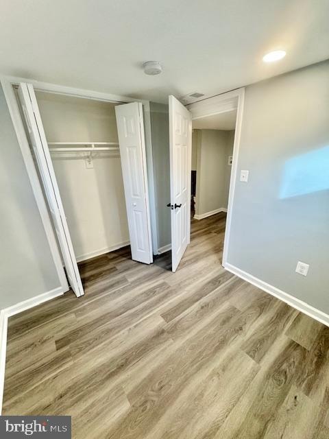 unfurnished bedroom with hardwood / wood-style floors and a closet