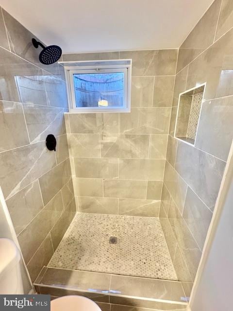 bathroom featuring tiled shower and toilet