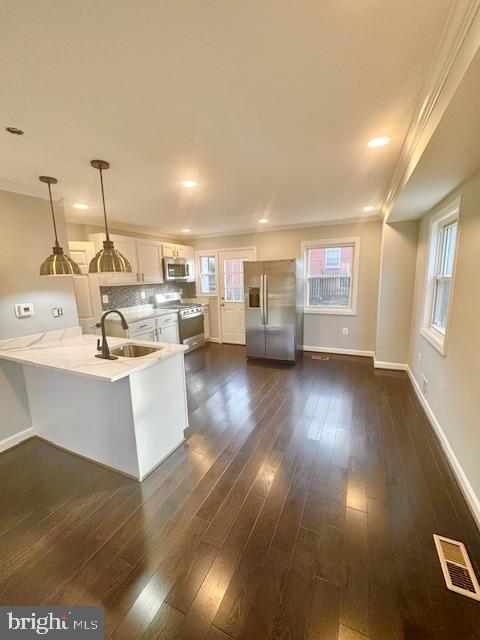 kitchen with white cabinets, dark hardwood / wood-style flooring, stainless steel appliances, and hanging light fixtures