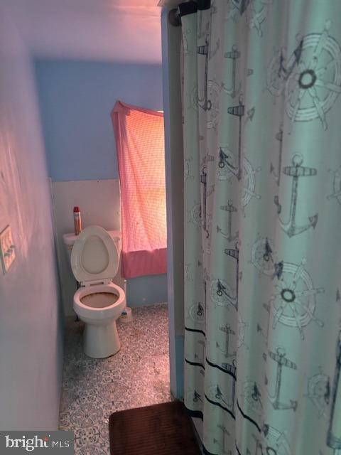 bathroom with a shower with shower curtain and toilet