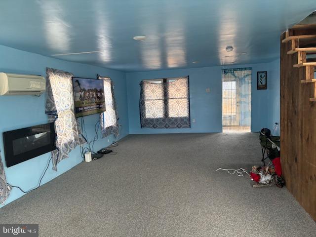 unfurnished living room with a wall mounted AC and carpet floors