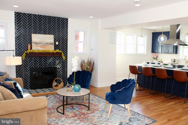 living room with a tile fireplace, light wood-type flooring, and a wealth of natural light