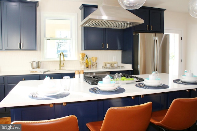 kitchen featuring blue cabinetry, a center island, a kitchen breakfast bar, custom exhaust hood, and appliances with stainless steel finishes