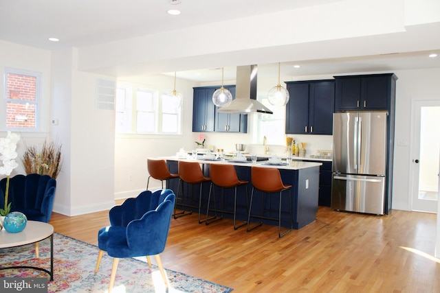 kitchen with pendant lighting, stainless steel fridge, light hardwood / wood-style flooring, and island range hood