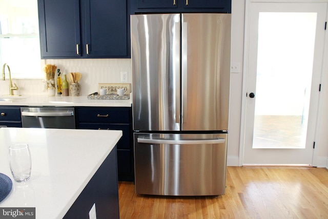 kitchen featuring sink, light hardwood / wood-style flooring, blue cabinets, and appliances with stainless steel finishes