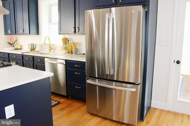 kitchen featuring light hardwood / wood-style floors, blue cabinets, sink, and appliances with stainless steel finishes