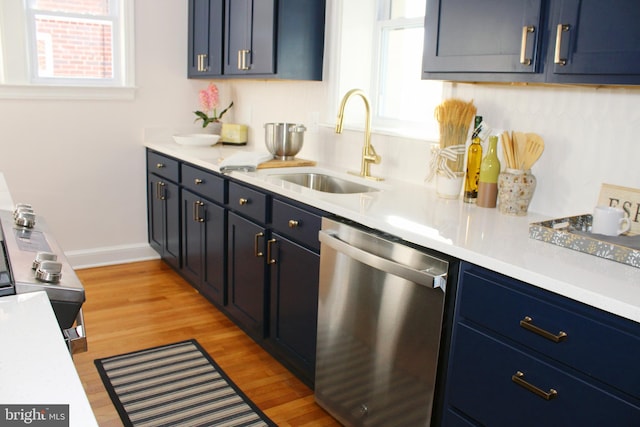 kitchen with blue cabinetry, dishwasher, light wood-type flooring, and sink