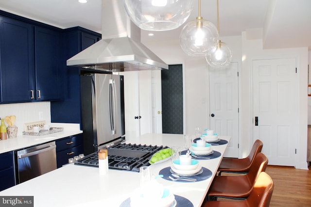 kitchen with hardwood / wood-style floors, blue cabinets, stainless steel appliances, and exhaust hood