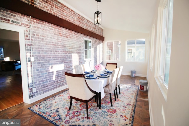 dining space with vaulted ceiling and brick wall