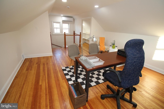 office space with vaulted ceiling, light hardwood / wood-style flooring, and an AC wall unit