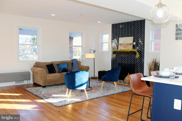 living room with a tile fireplace, wood-type flooring, and plenty of natural light