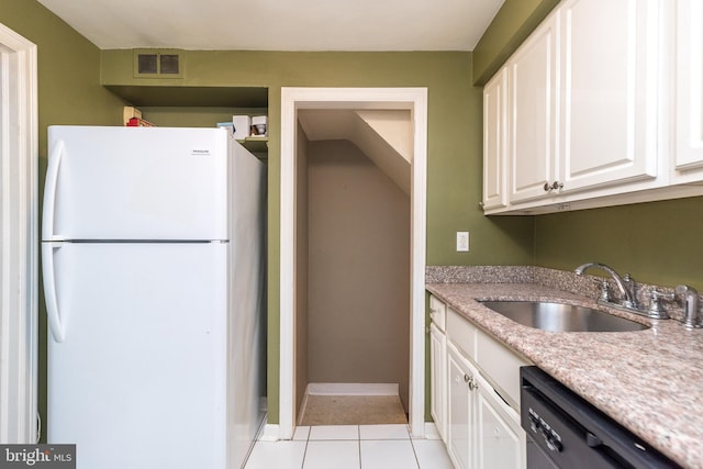 kitchen with stainless steel dishwasher, sink, light tile patterned floors, white refrigerator, and white cabinets