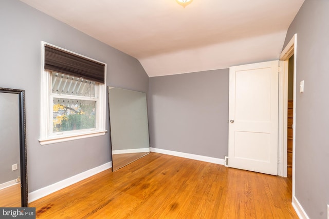 unfurnished bedroom featuring lofted ceiling and hardwood / wood-style flooring