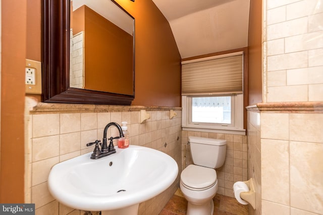 bathroom with tile patterned flooring, toilet, sink, and tile walls