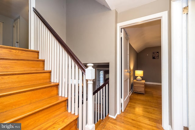 stairway featuring wood-type flooring and vaulted ceiling