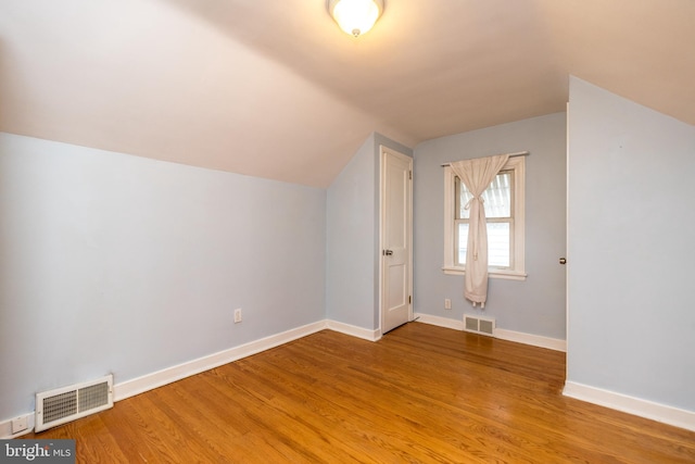 additional living space with light hardwood / wood-style flooring and lofted ceiling