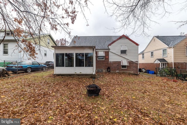 rear view of property featuring a sunroom and an outdoor fire pit