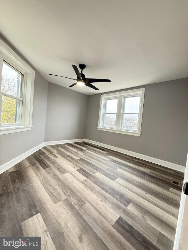 empty room with ceiling fan, hardwood / wood-style floors, a healthy amount of sunlight, and vaulted ceiling