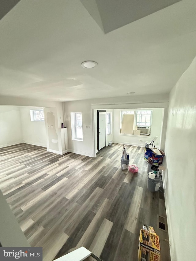 living room featuring cooling unit, wood-type flooring, and a wealth of natural light