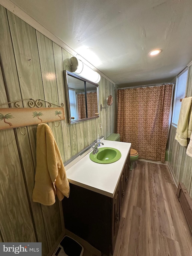 bathroom featuring vanity, hardwood / wood-style flooring, toilet, and wooden walls