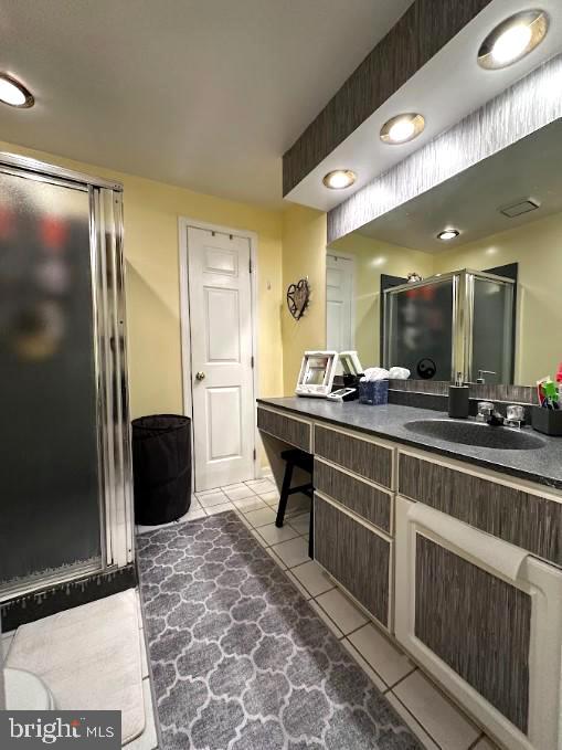 bathroom with tile patterned floors, vanity, and an enclosed shower