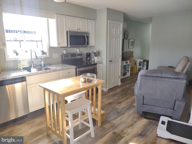 kitchen with dark hardwood / wood-style floors, white cabinetry, sink, and appliances with stainless steel finishes