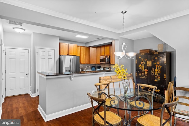 kitchen with dark wood-type flooring, stainless steel appliances, kitchen peninsula, decorative light fixtures, and ornamental molding