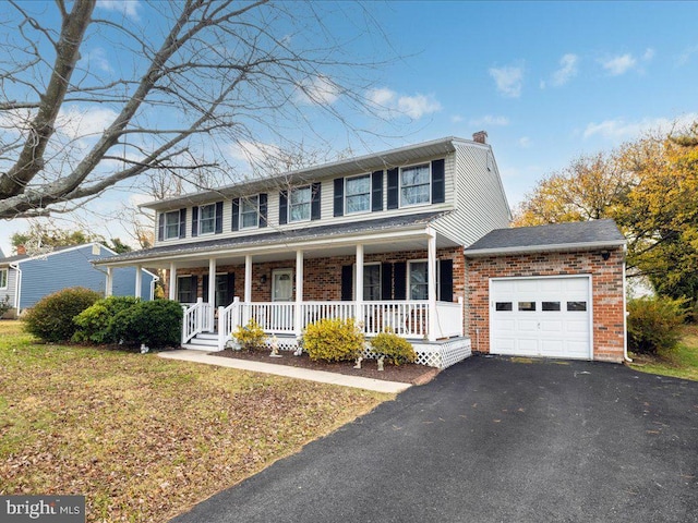 colonial inspired home with a porch, a garage, and a front lawn