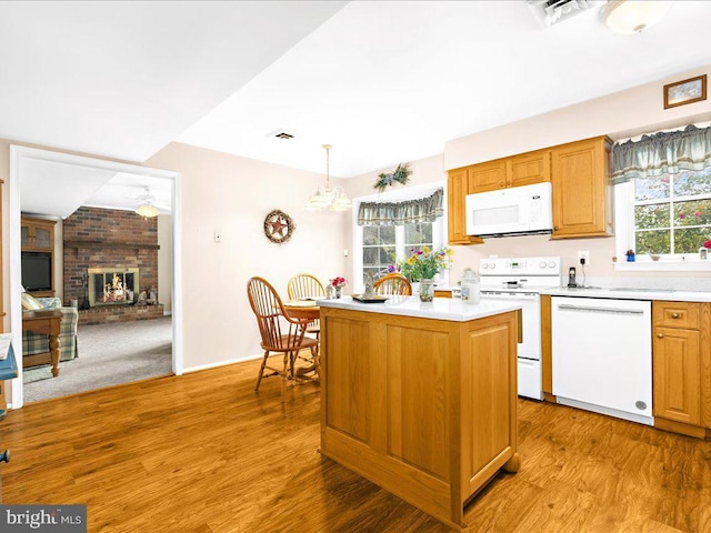 kitchen with light wood-type flooring, white appliances, decorative light fixtures, and a healthy amount of sunlight