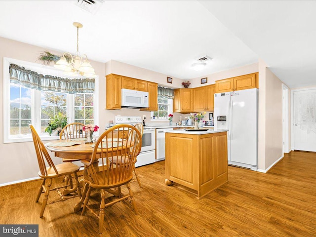 kitchen featuring a center island, an inviting chandelier, light hardwood / wood-style flooring, decorative light fixtures, and white appliances