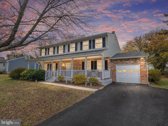 view of front of house featuring covered porch, a garage, and a lawn