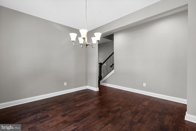 spare room featuring dark hardwood / wood-style flooring and a notable chandelier