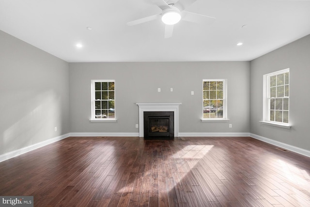 unfurnished living room with dark hardwood / wood-style floors, ceiling fan, and a wealth of natural light