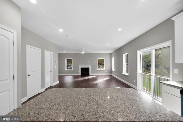 unfurnished living room featuring ceiling fan and dark wood-type flooring