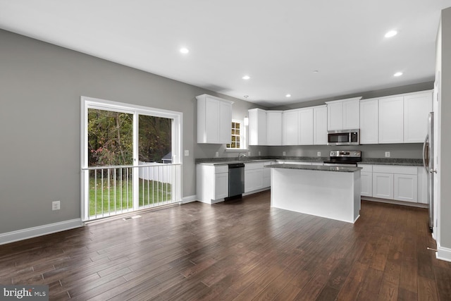 kitchen with appliances with stainless steel finishes, dark hardwood / wood-style flooring, white cabinetry, and a wealth of natural light