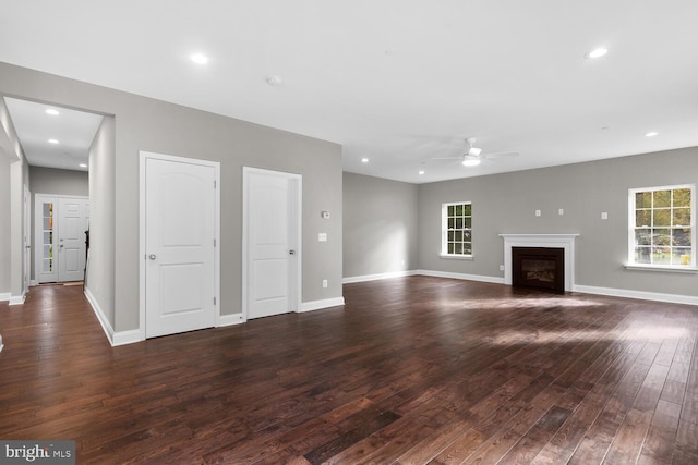 unfurnished living room with dark hardwood / wood-style floors, a wealth of natural light, and ceiling fan